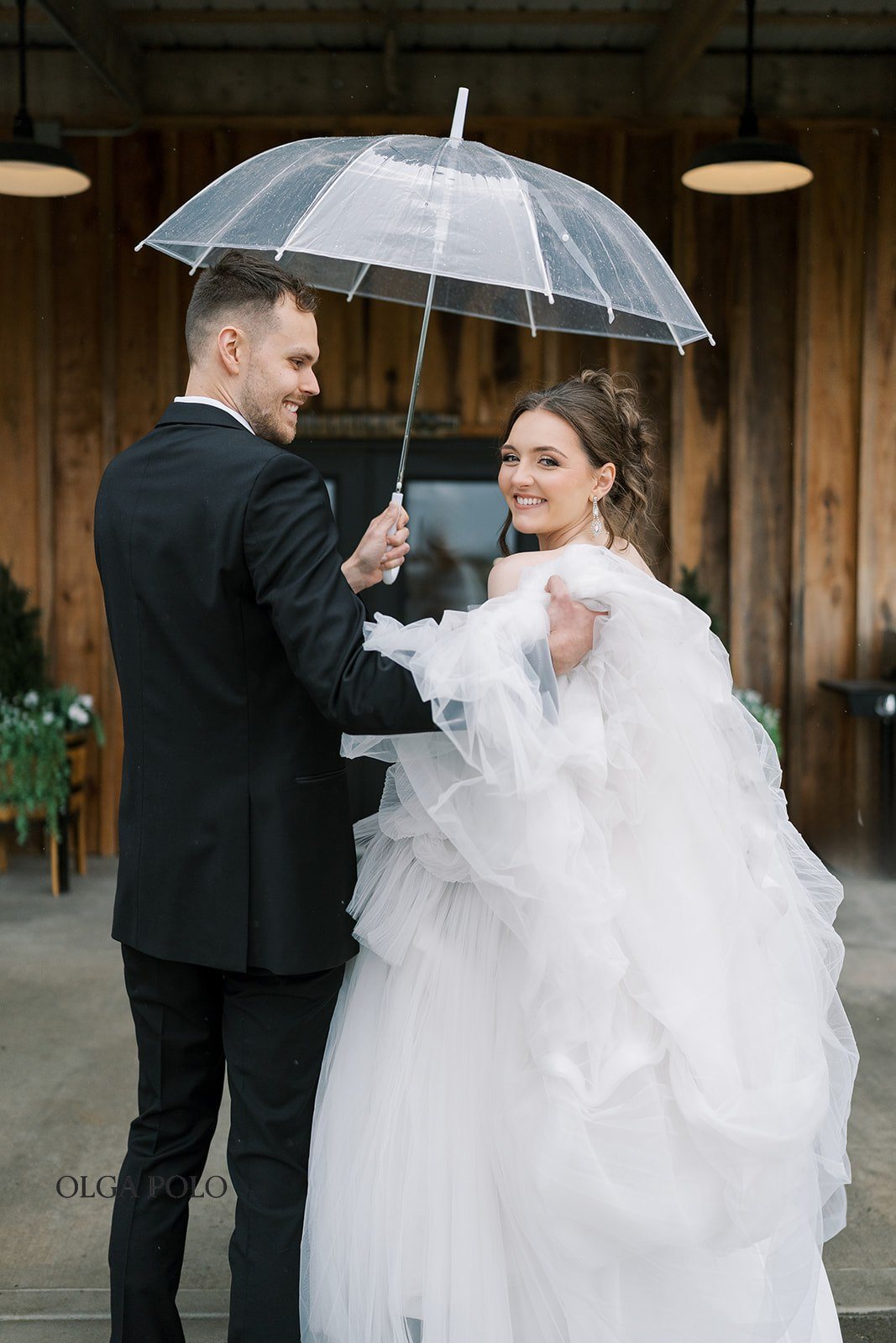 Maia and Troy posing together beneath a clear umbrella