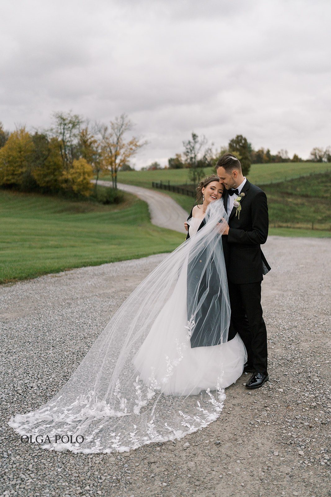 Maia and Troy walking outdoors with Maia's veil moving behind them