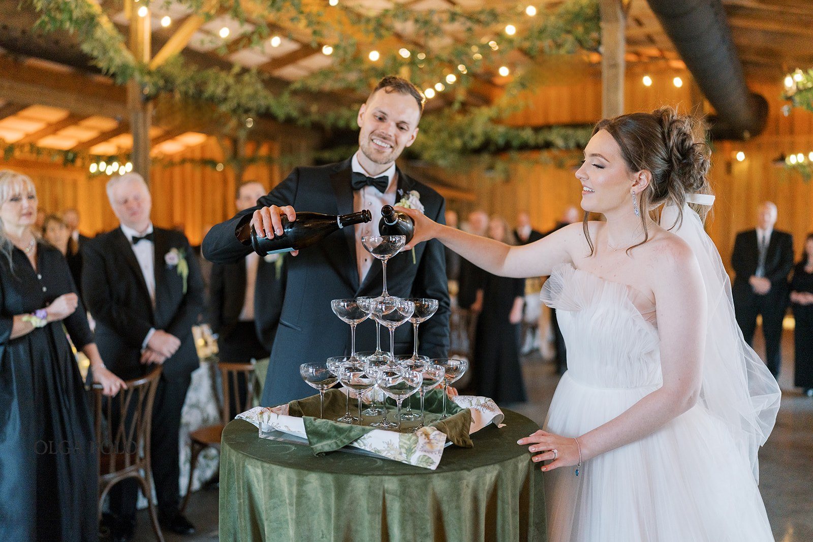 Maia and Troy pouring champagne into a tower during the reception