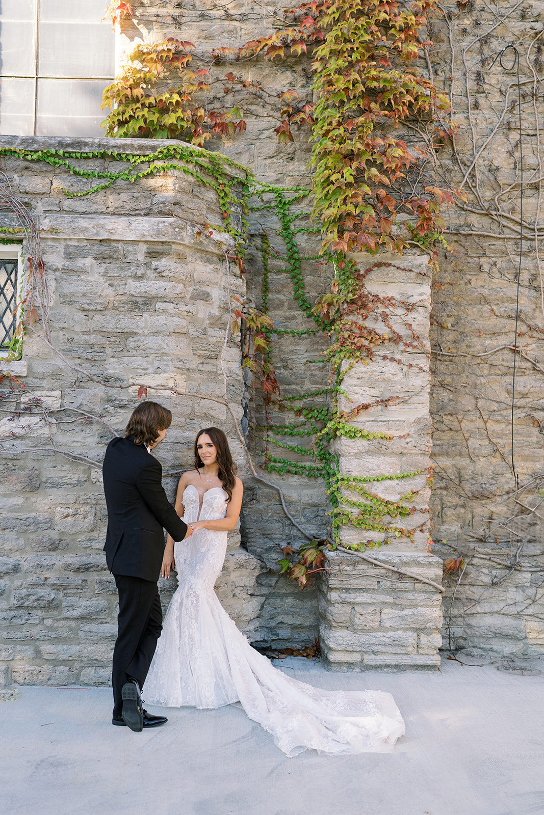 Ronnie and Patrick posing together beside a textured stone wall