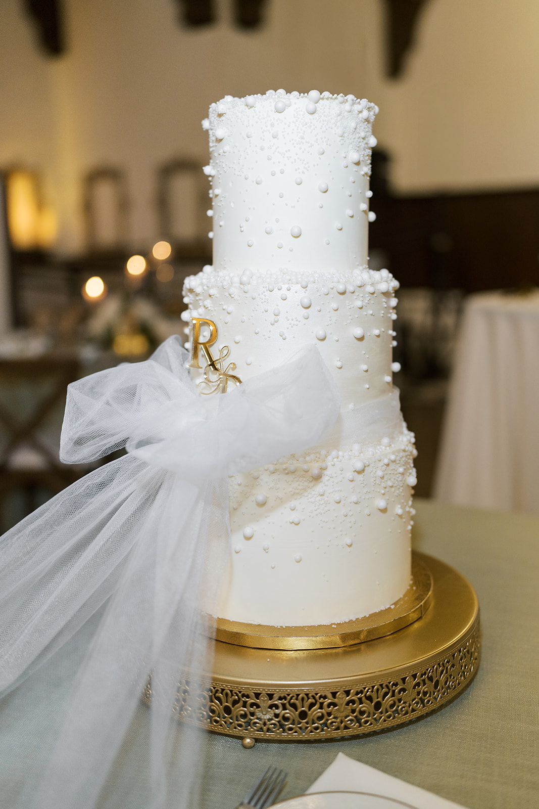 White tiered wedding cake with delicate floral detailing at Ronnie and Patrick's reception
