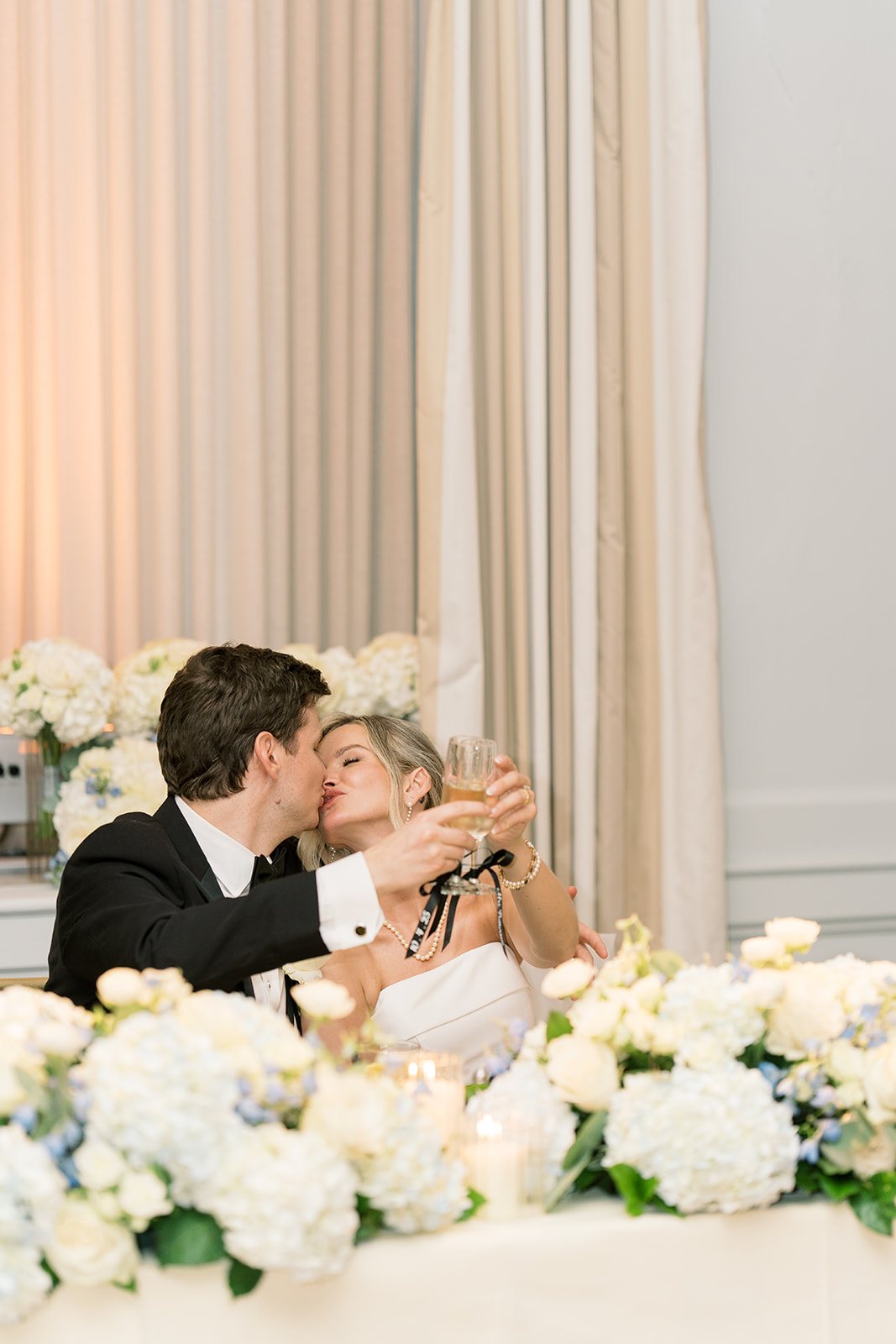 Andee and Quinn kissing at their sweetheart table during the reception