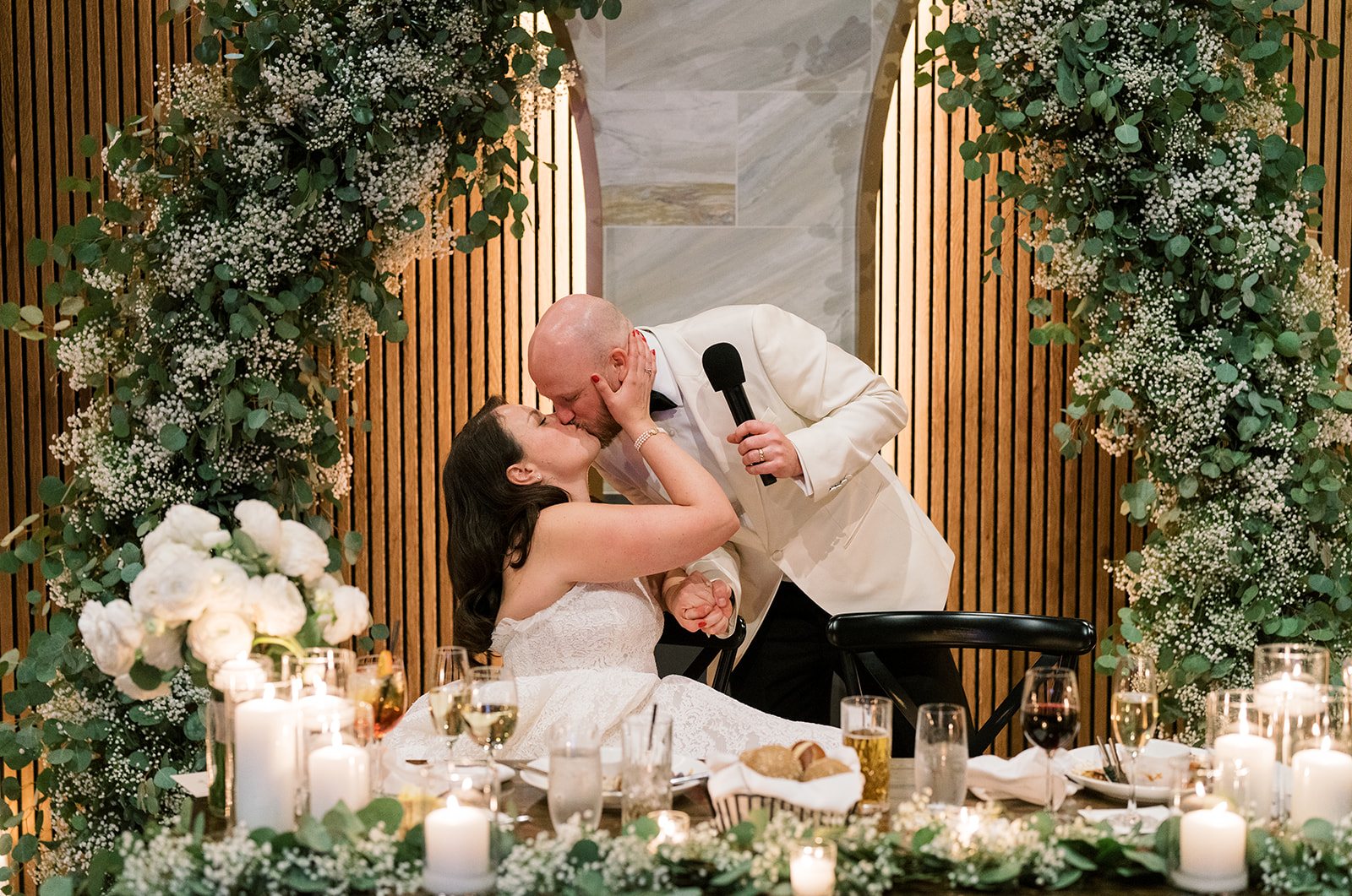 Clint and Ania kissing at their sweetheart table during the reception