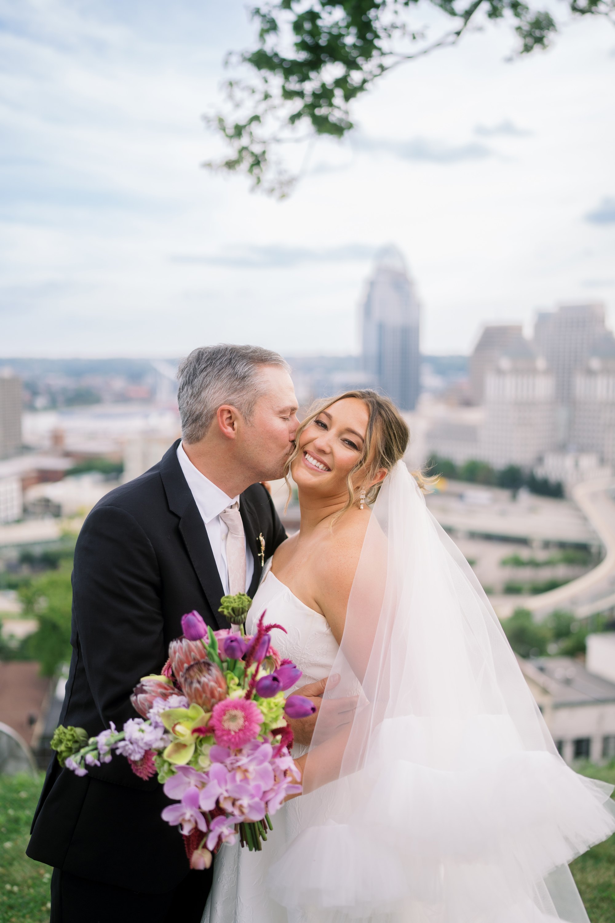 Kent and Nicolette kissing with the Cincinnati skyline behind them from Mt. Adams