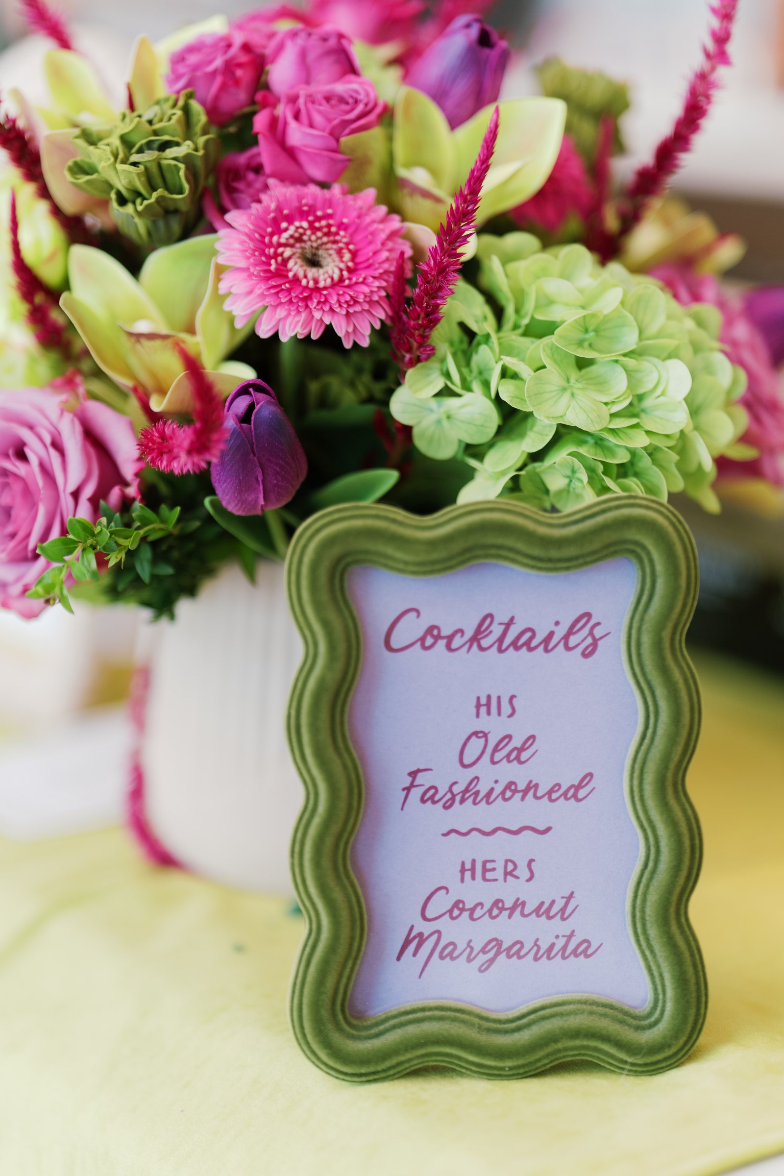 Signature cocktail sign surrounded by colorful flowers at Kent and Nicolette's reception