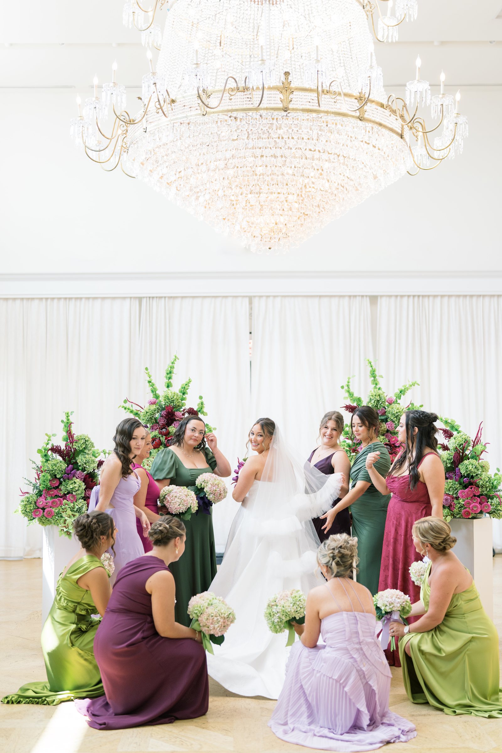 Nicolette surrounded by bridesmaids beneath the chandelier at The View at Mt. Adams