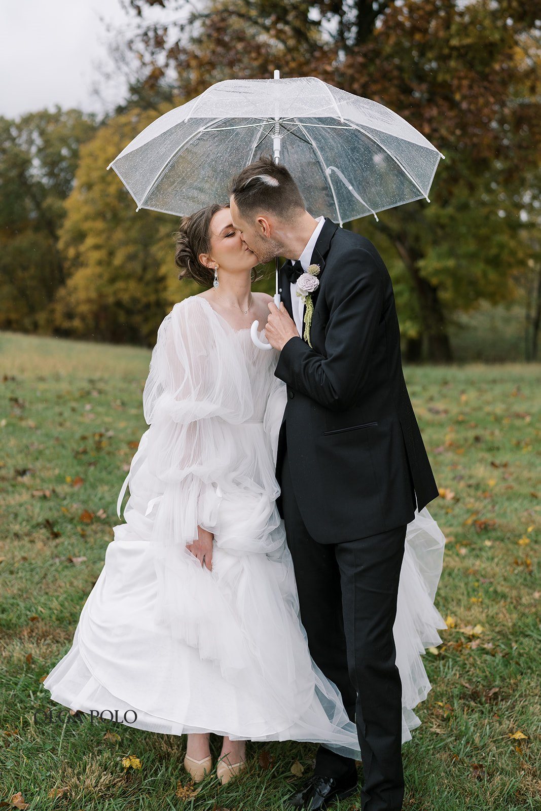 Maia and Troy together beneath clear umbrellas during their wedding portraits