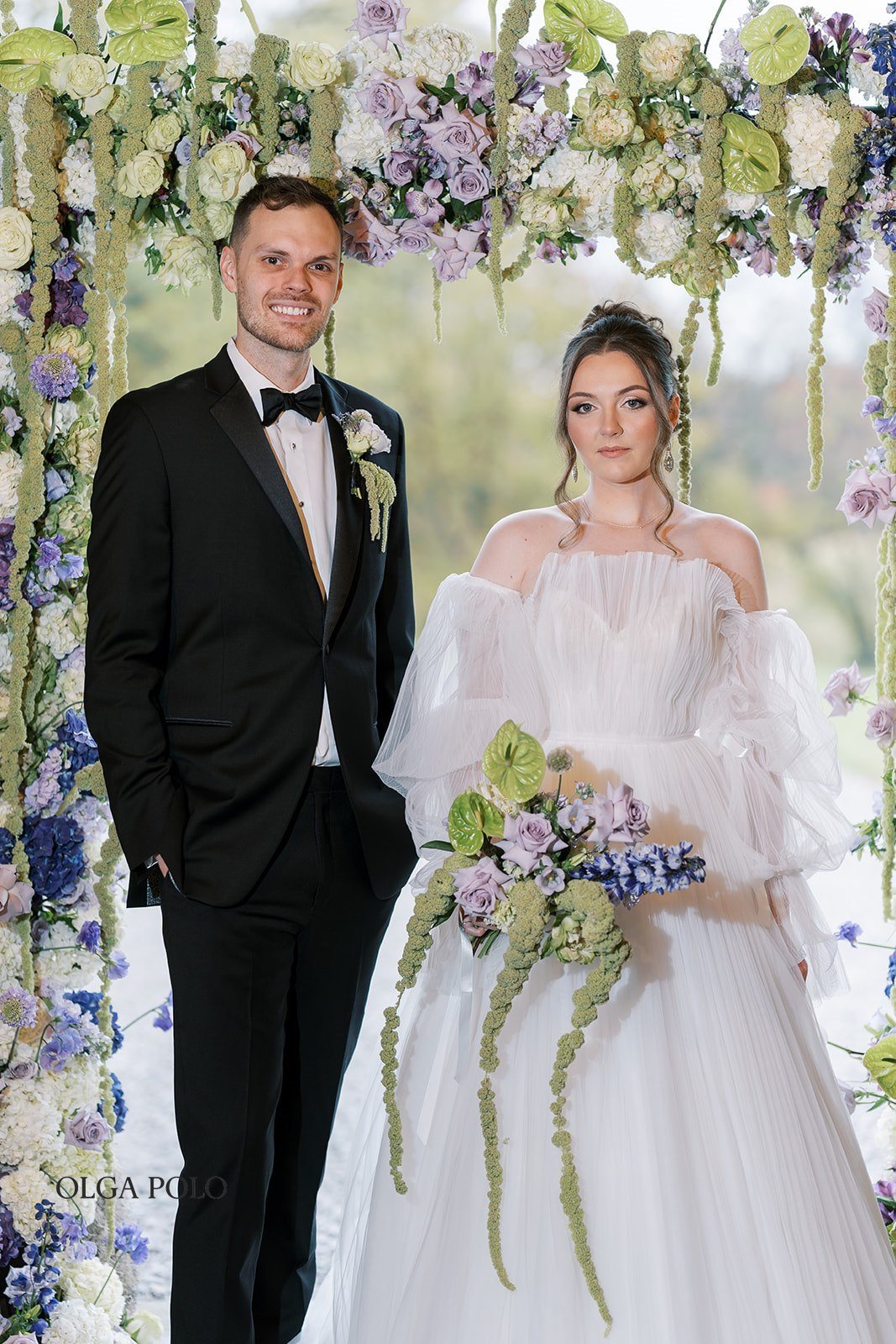 Maia and Troy together beneath the floral ceremony installation
