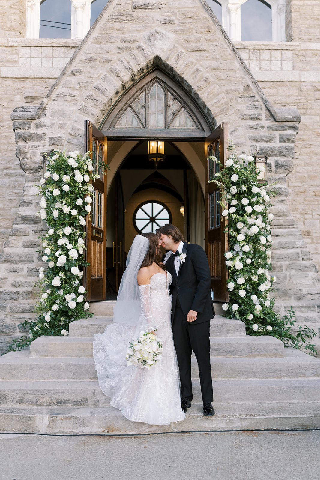 Ronnie and Patrick together beneath white florals at The Palomar Cincinnati's stone entrance