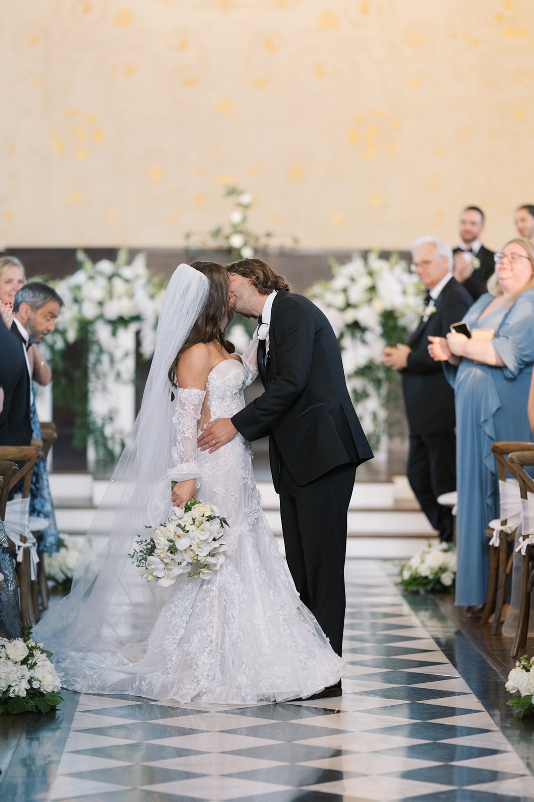 Ronnie and Patrick kissing during their ceremony on The Palomar Cincinnati's checkerboard aisle