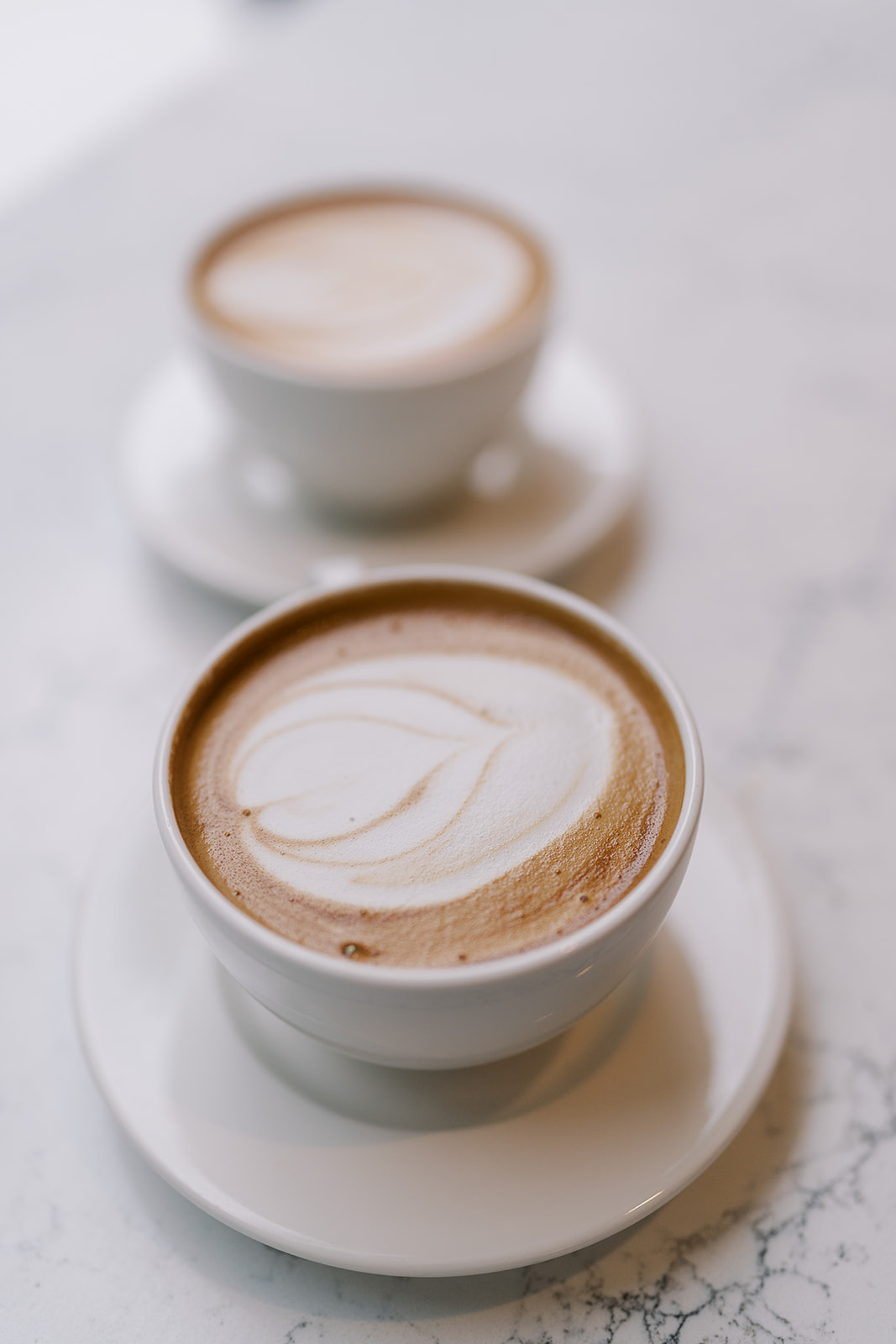 Two cappuccino cups on a café table at the start of Frank and Noelle's engagement session