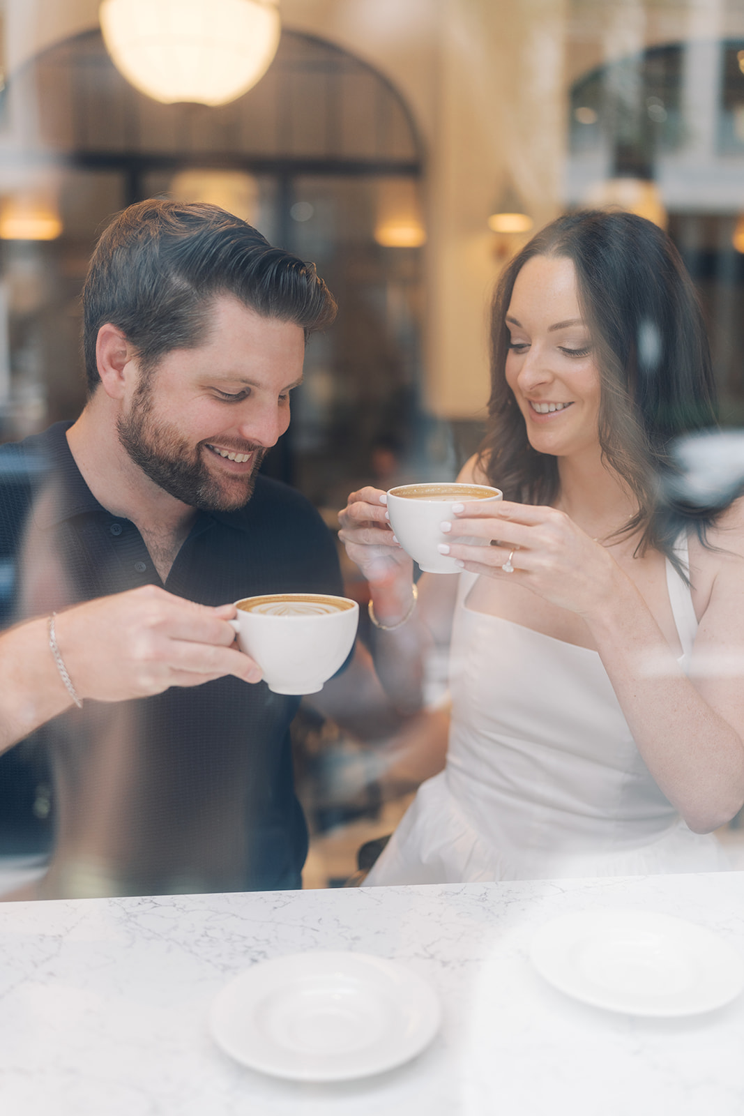 Frank and Noelle smiling together over coffee at a café table