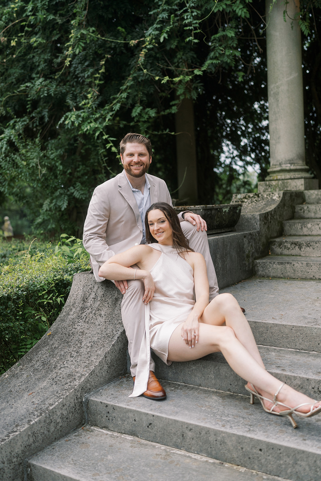 Frank and Noelle seated together on a curved stone garden wall at Laurel Court