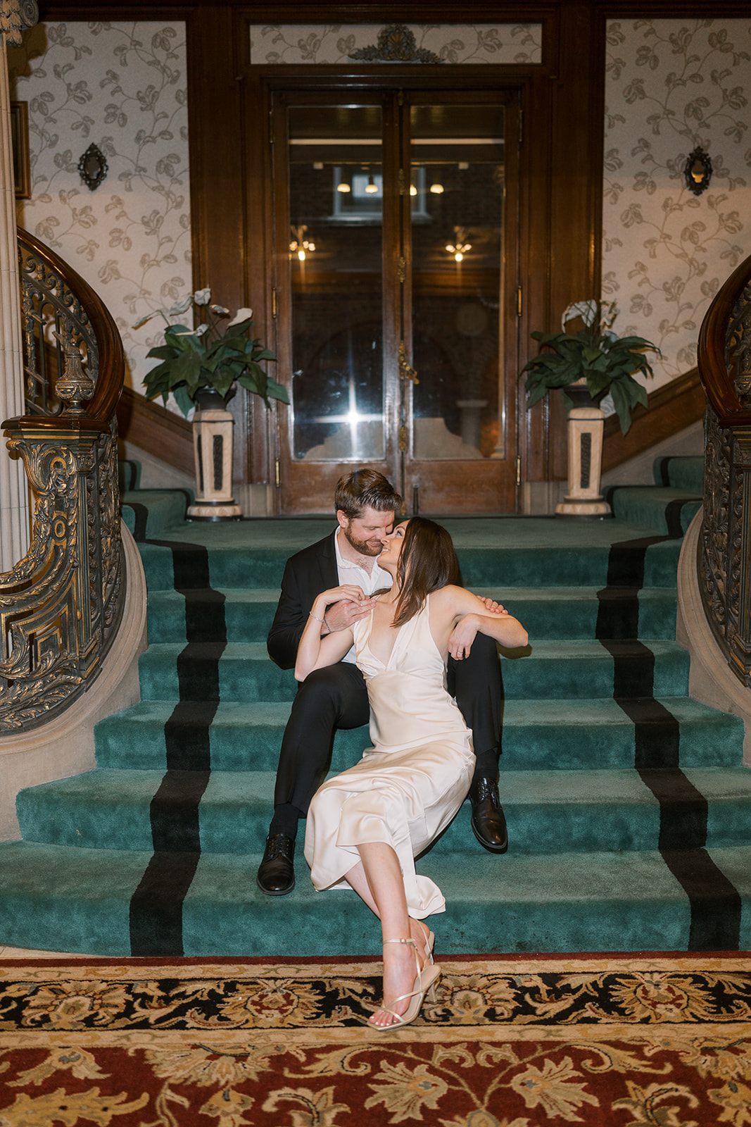 Frank and Noelle seated together on the grand staircase at Laurel Court
