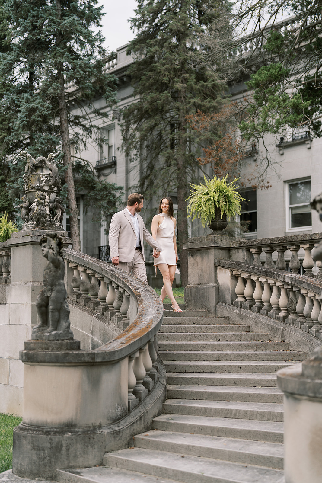 Frank and Noelle walking down a curved stone staircase at Laurel Court
