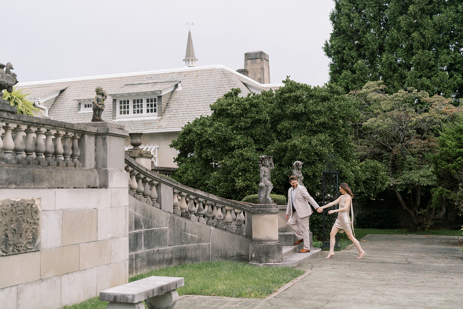 Wide view of Frank and Noelle walking beside Laurel Court's stone terrace and estate house