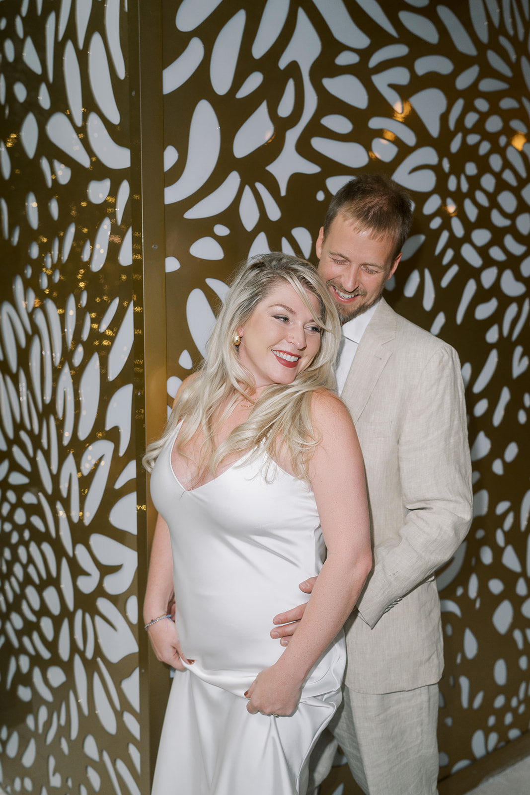 Josh and Autumn together beside a decorative interior wall