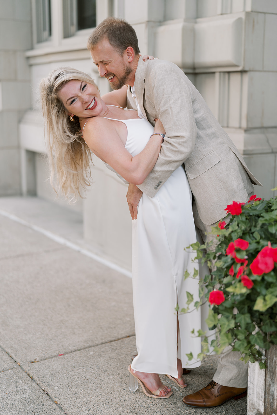 Josh and Autumn standing together with flowers outside The Lytle Park Hotel