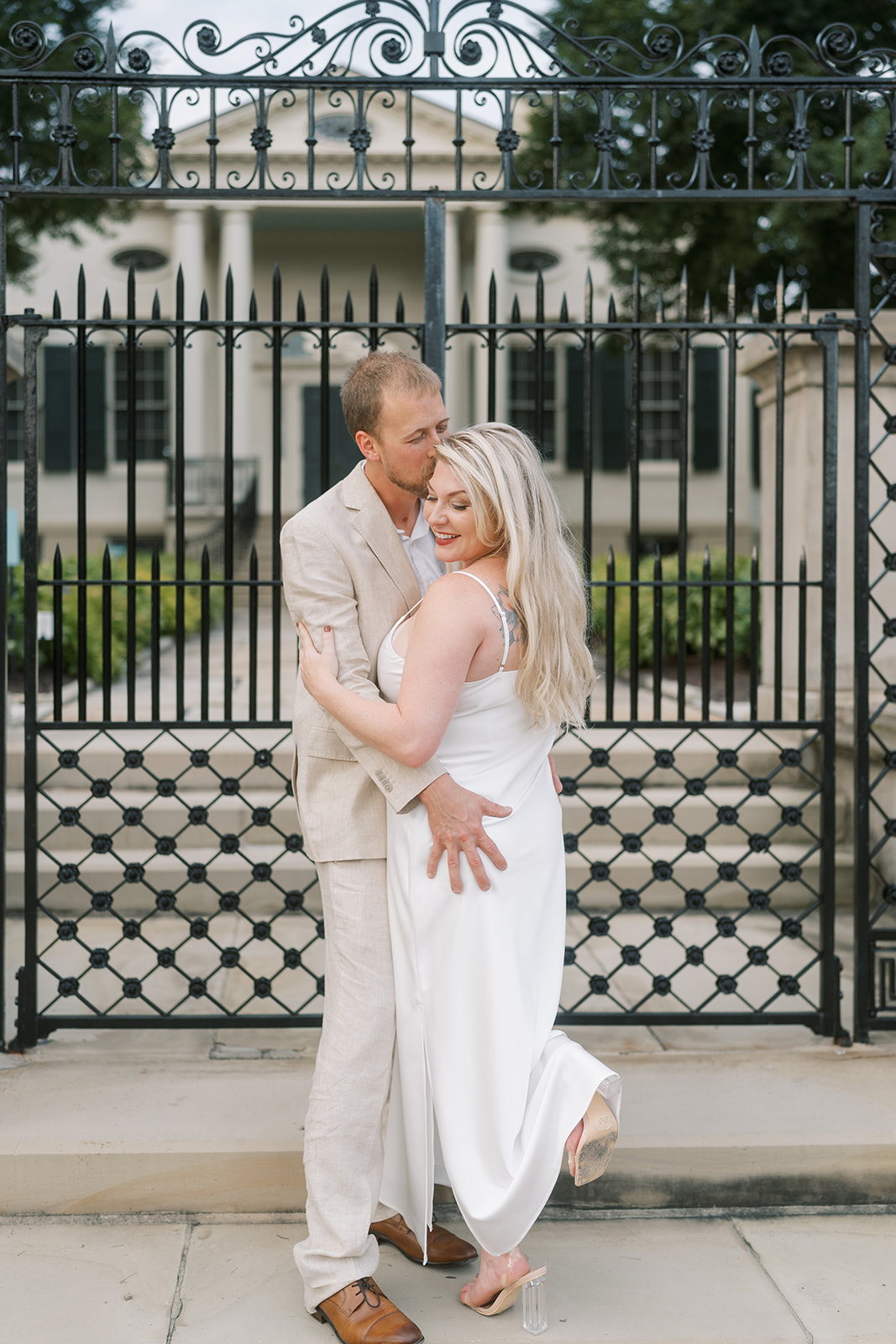 Josh and Autumn embracing beside an exterior iron gate
