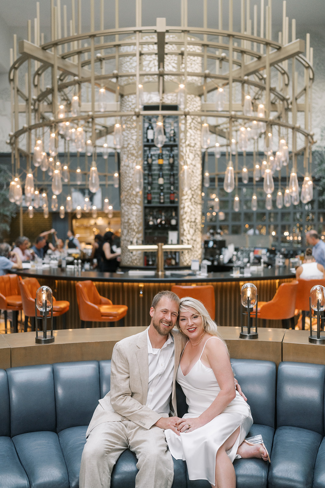 Josh and Autumn seated beneath the circular chandelier in the lobby of The Lytle Park Hotel