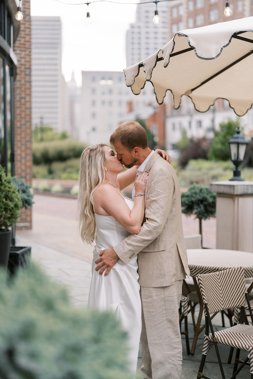 Josh and Autumn kissing on the terrace with the Cincinnati skyline behind them