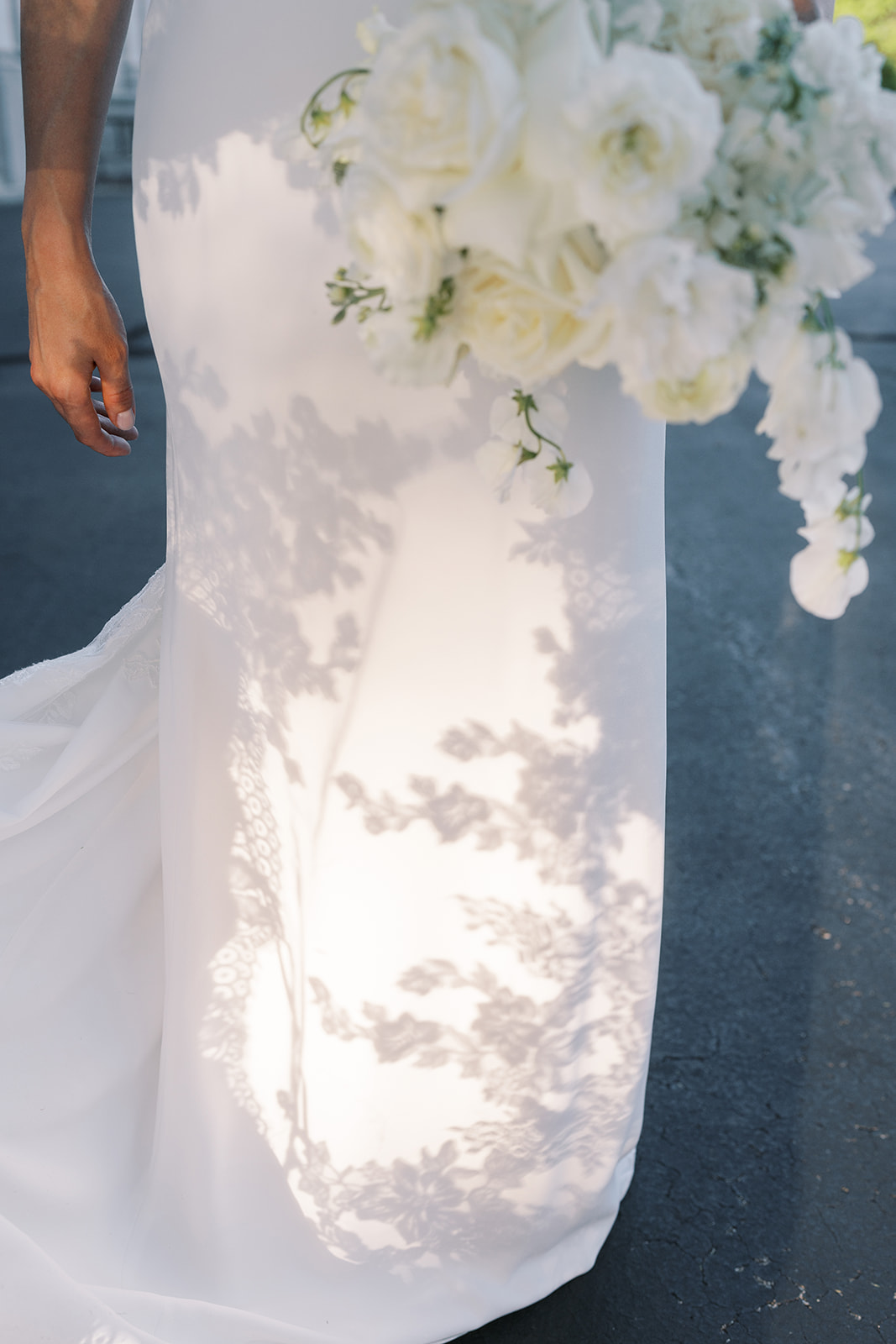Julia's white bouquet casting floral shadows across her wedding dress