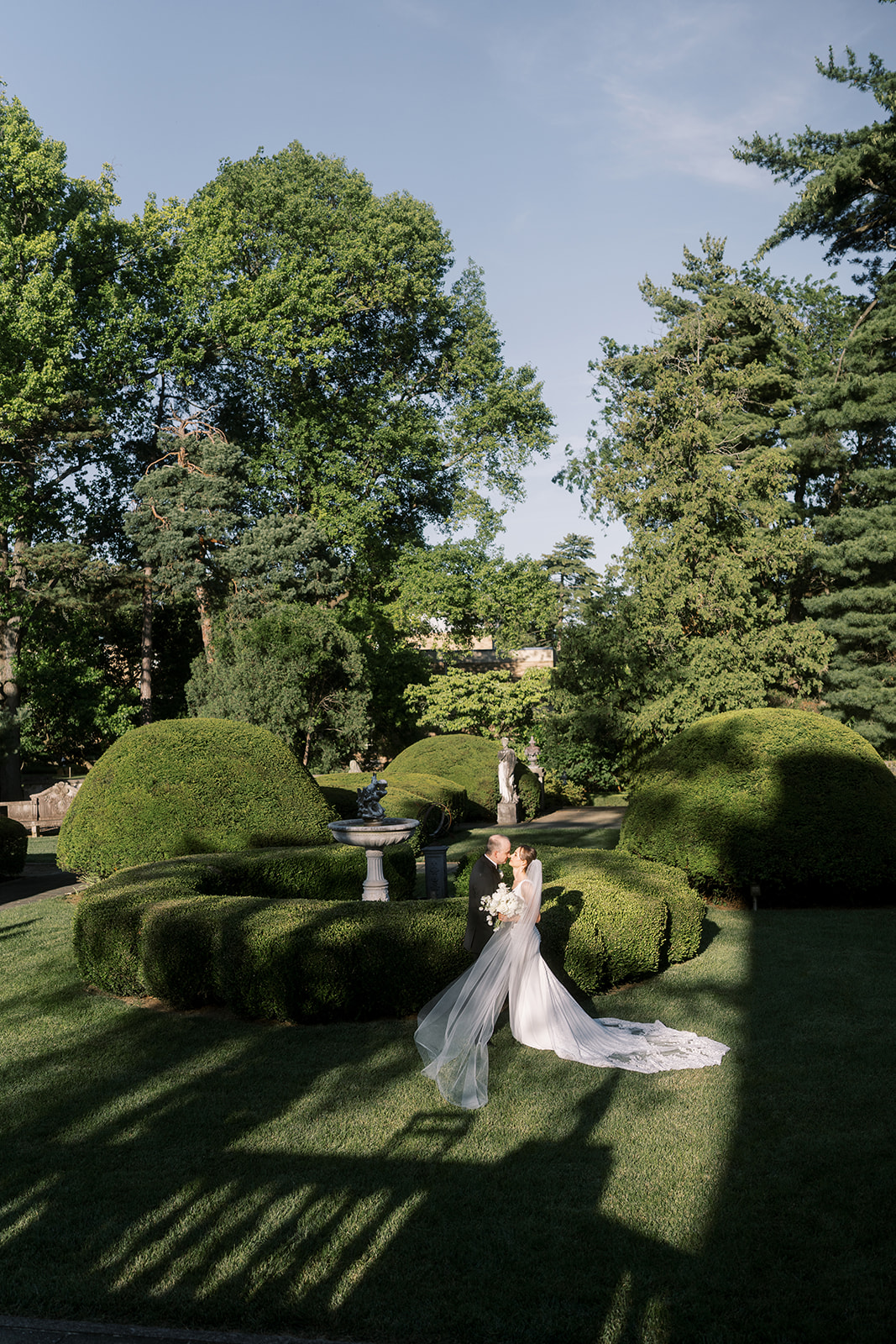 Michael and Julia standing together among the sculpted hedges at Laurel Court