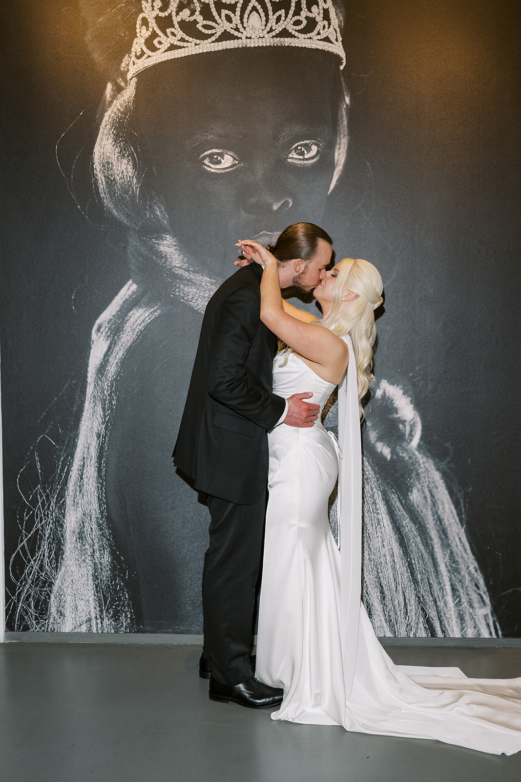 Niamh and Titus kissing in front of black-and-white portrait artwork at 21c Museum Hotel Cincinnati