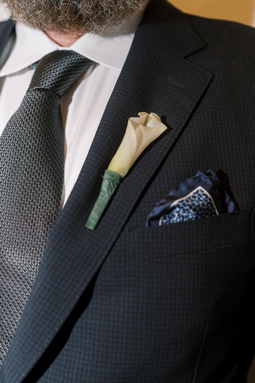 Close detail of Titus's black wedding suit and boutonniere