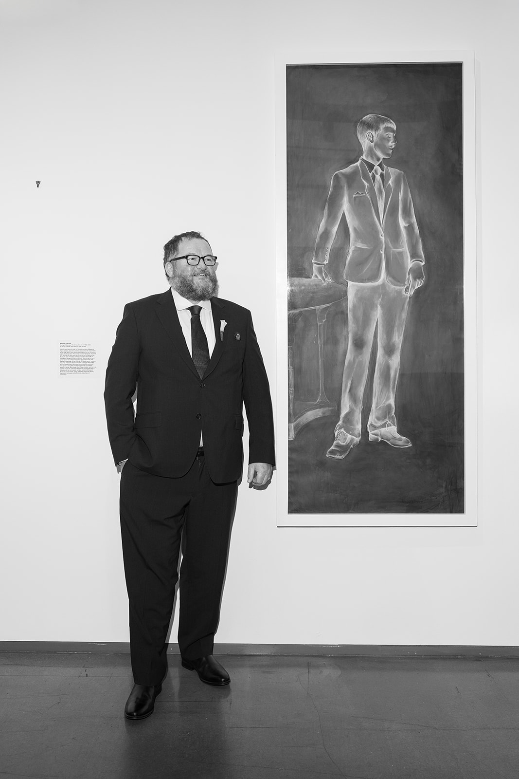 Black-and-white portrait of Titus in his wedding suit beside artwork at 21c Museum Hotel Cincinnati