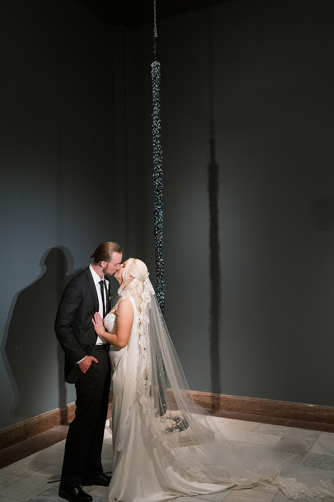 Niamh and Titus kissing inside a dark Cincinnati Art Museum gallery