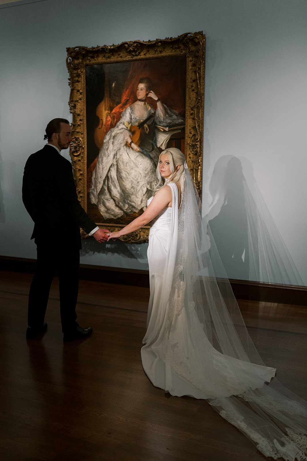 Niamh and Titus holding hands in front of a framed painting at Cincinnati Art Museum