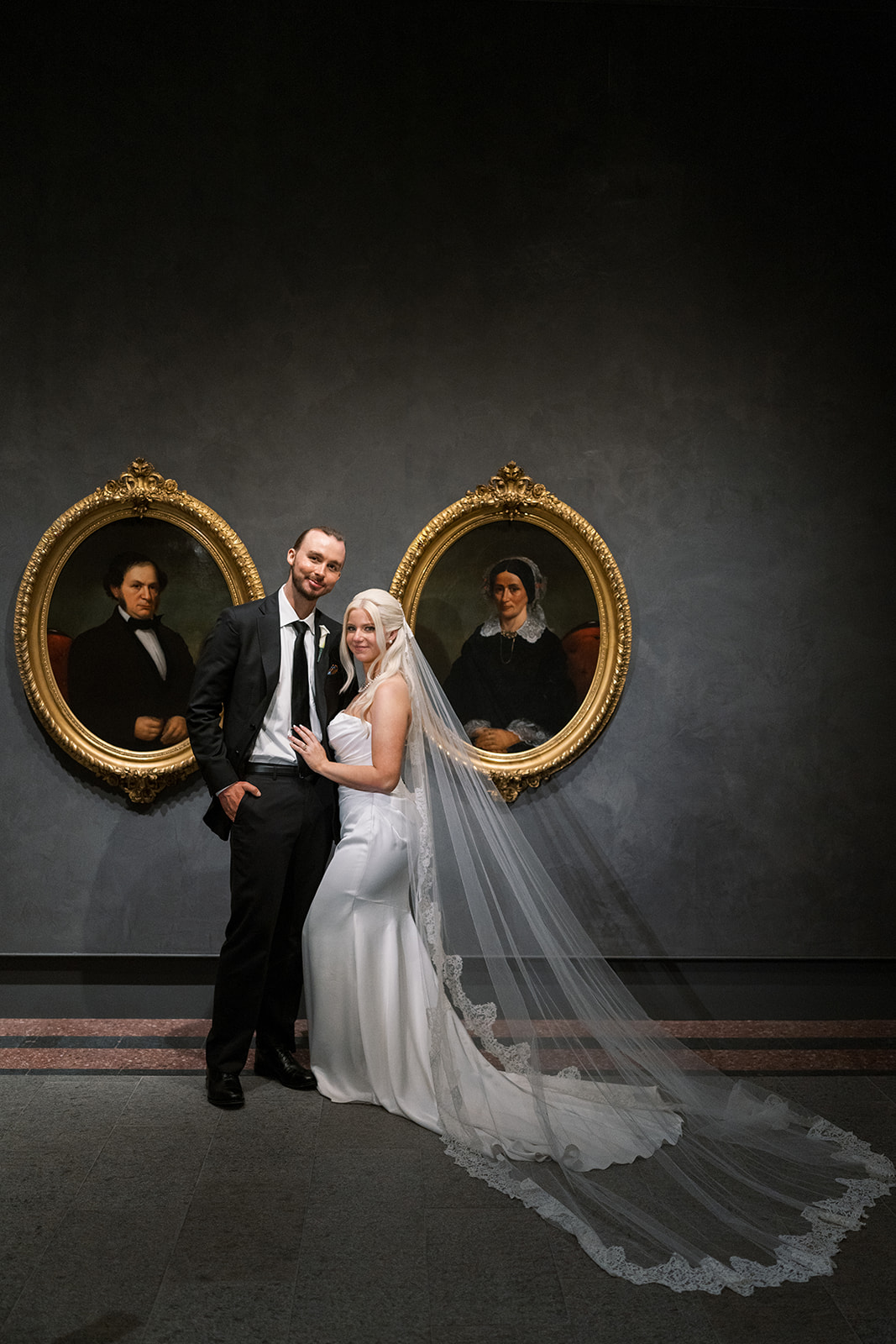 Niamh and Titus together between two oval portraits at Cincinnati Art Museum