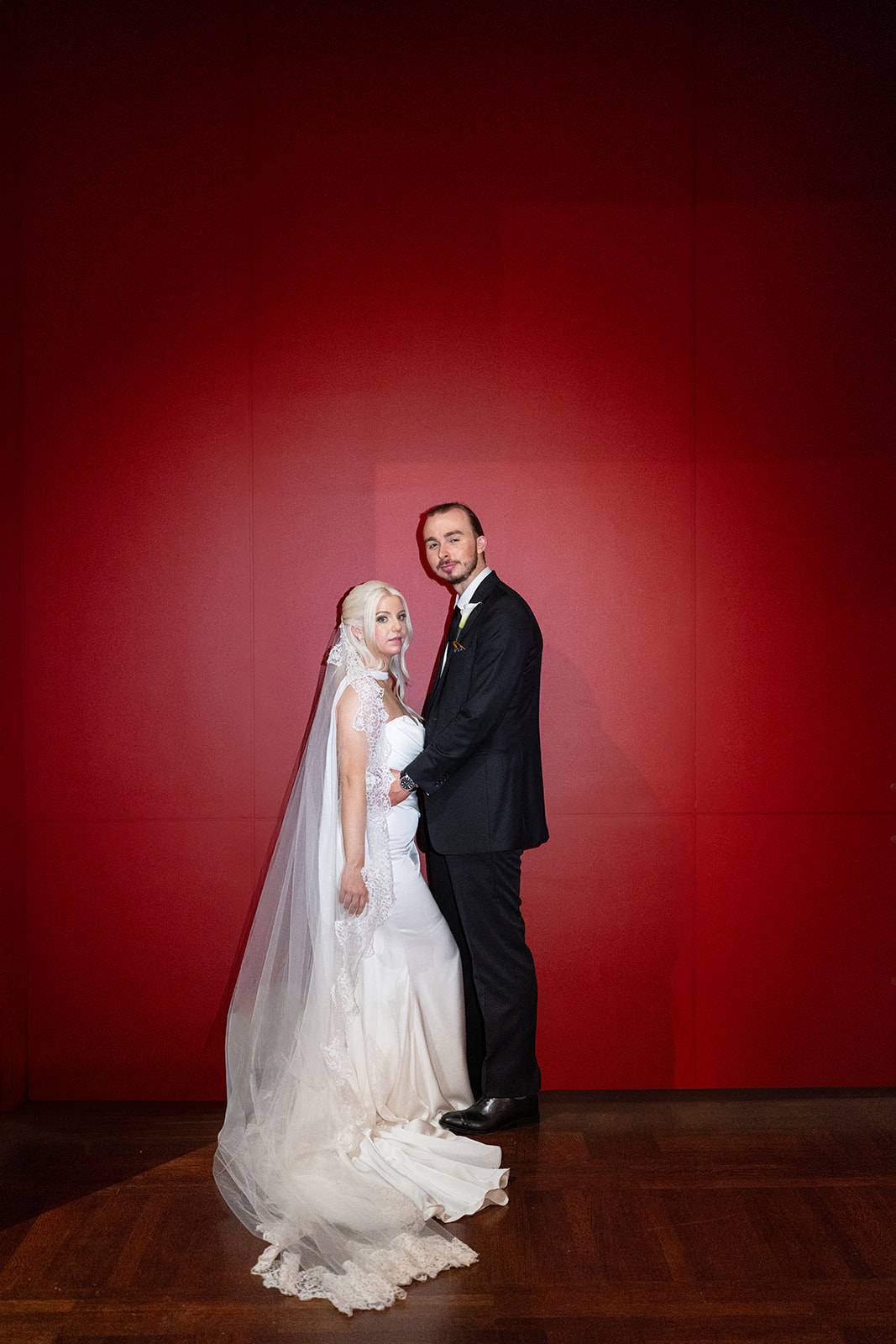 Niamh and Titus standing together against a rich red gallery wall at Cincinnati Art Museum