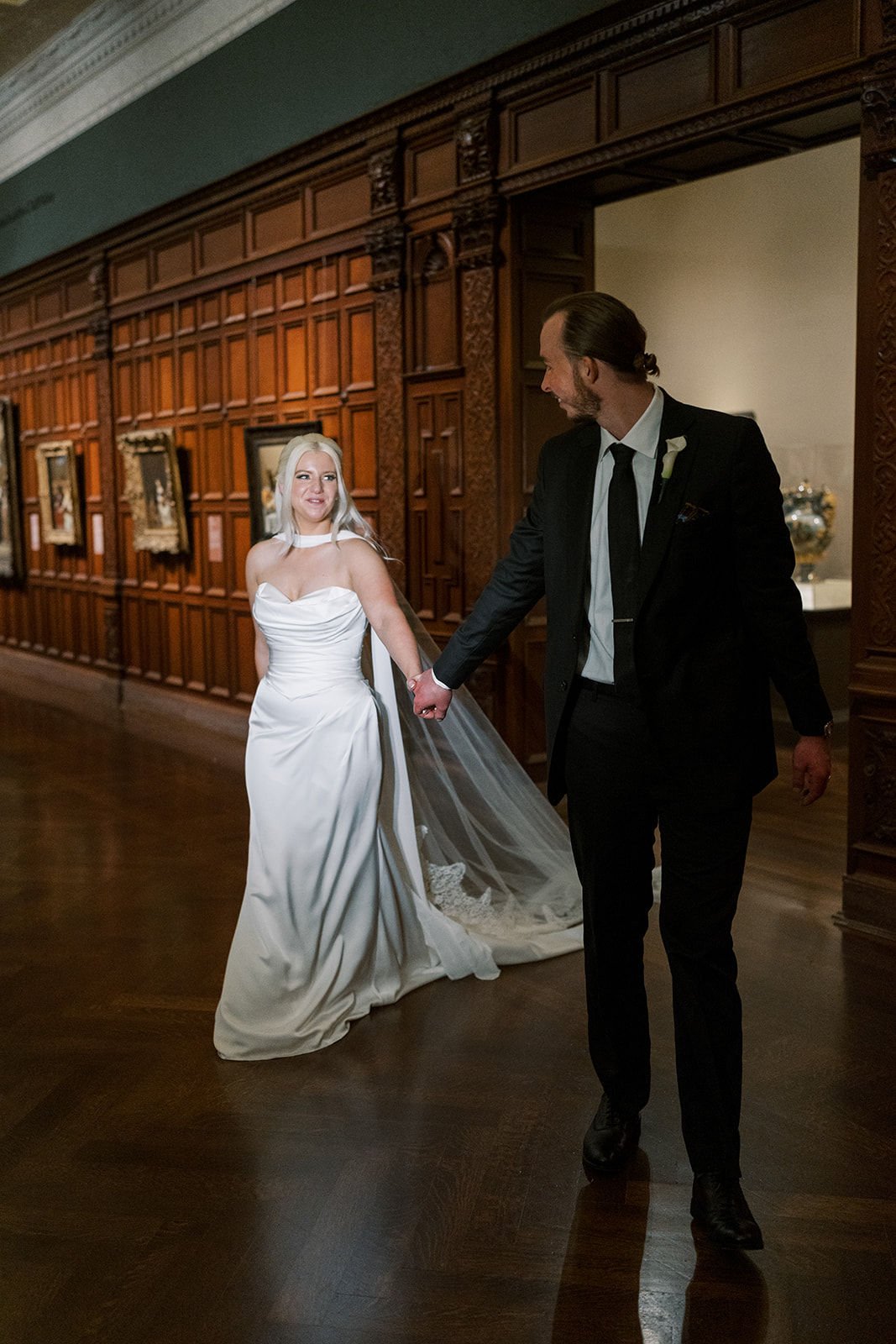 Niamh and Titus walking through a wood-paneled gallery at Cincinnati Art Museum
