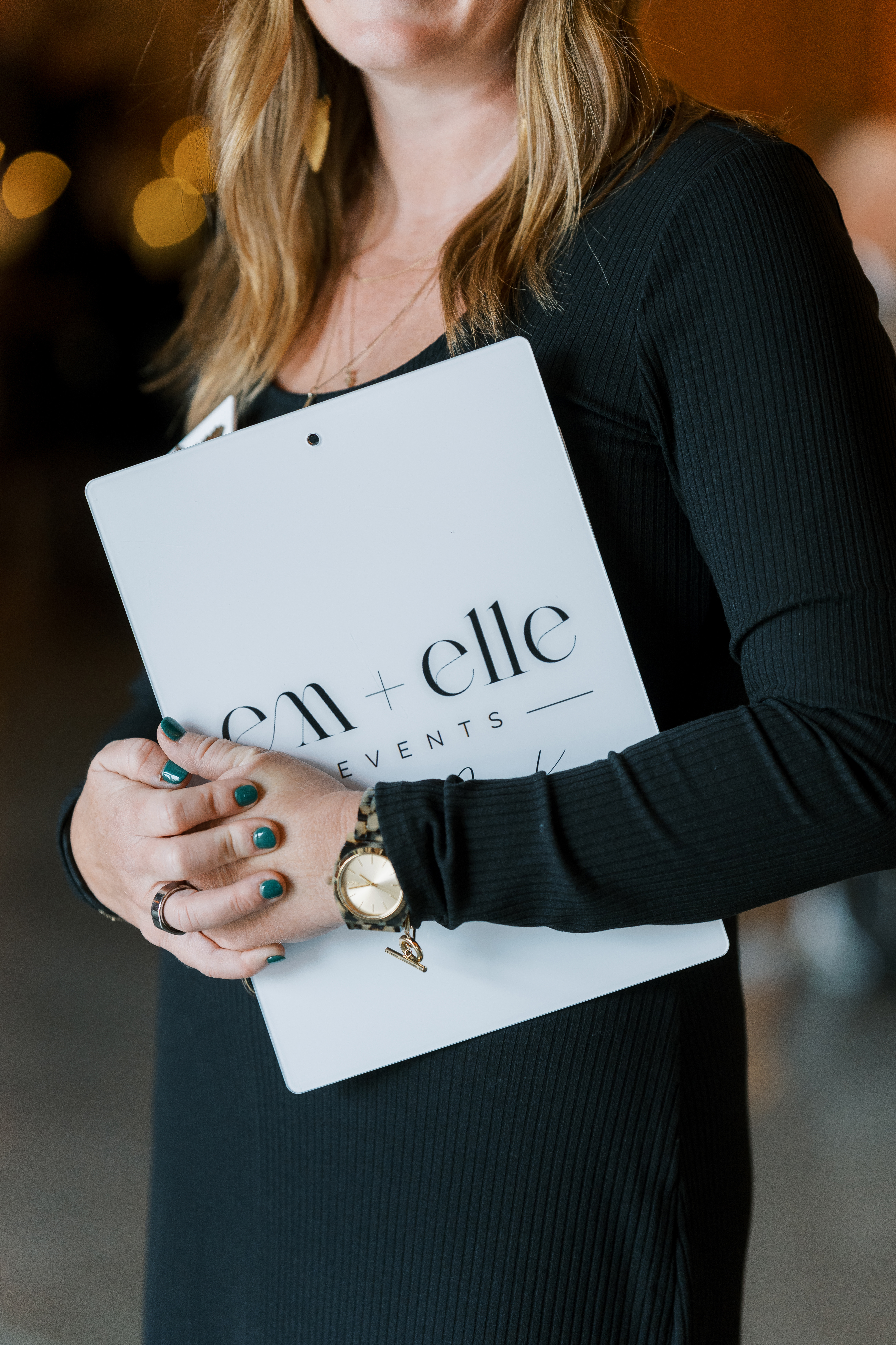 Em + Elle Events planning folder held by Leeann McKay during a wedding reception