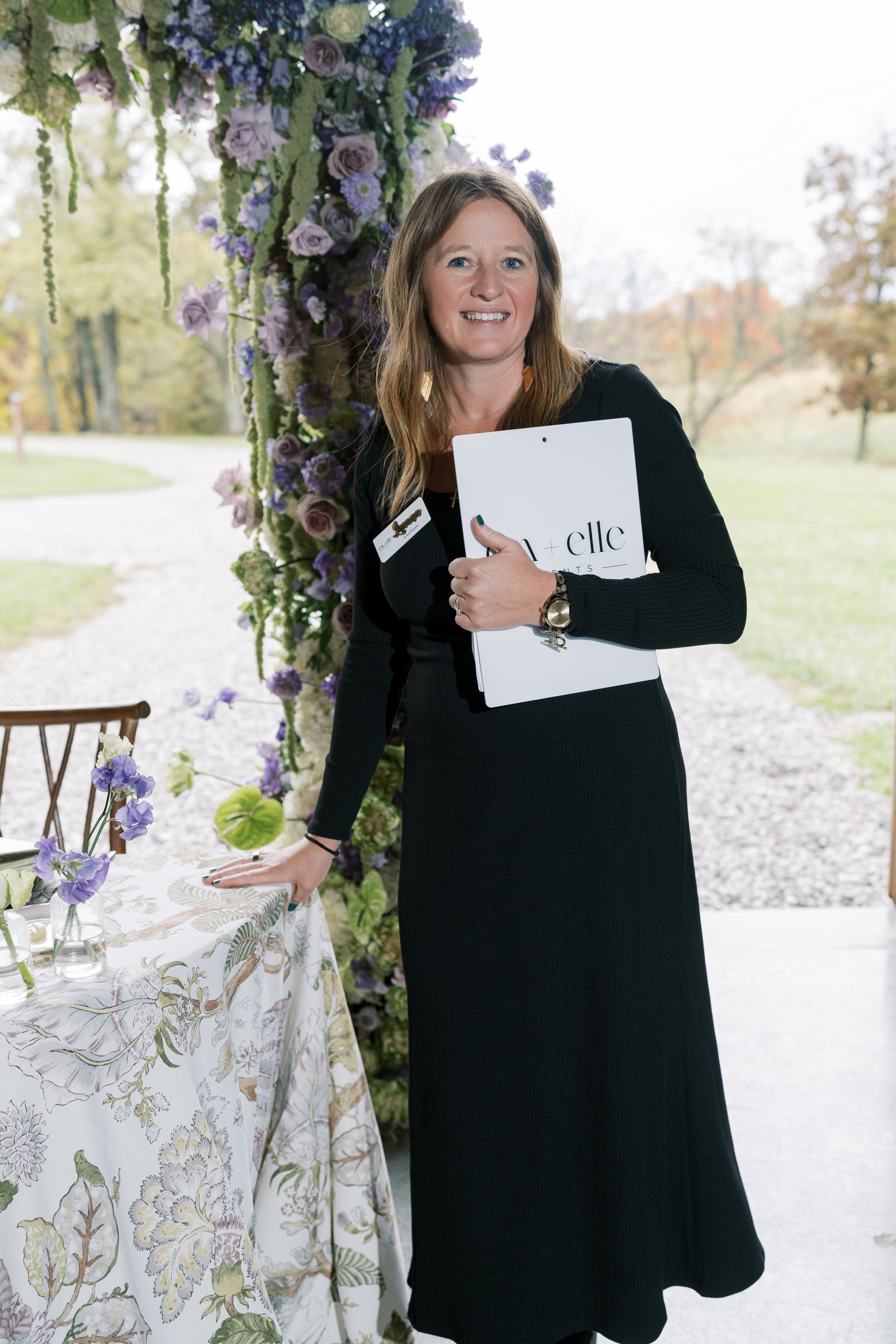 Leeann McKay of Em + Elle Events beside a floral ceremony installation
