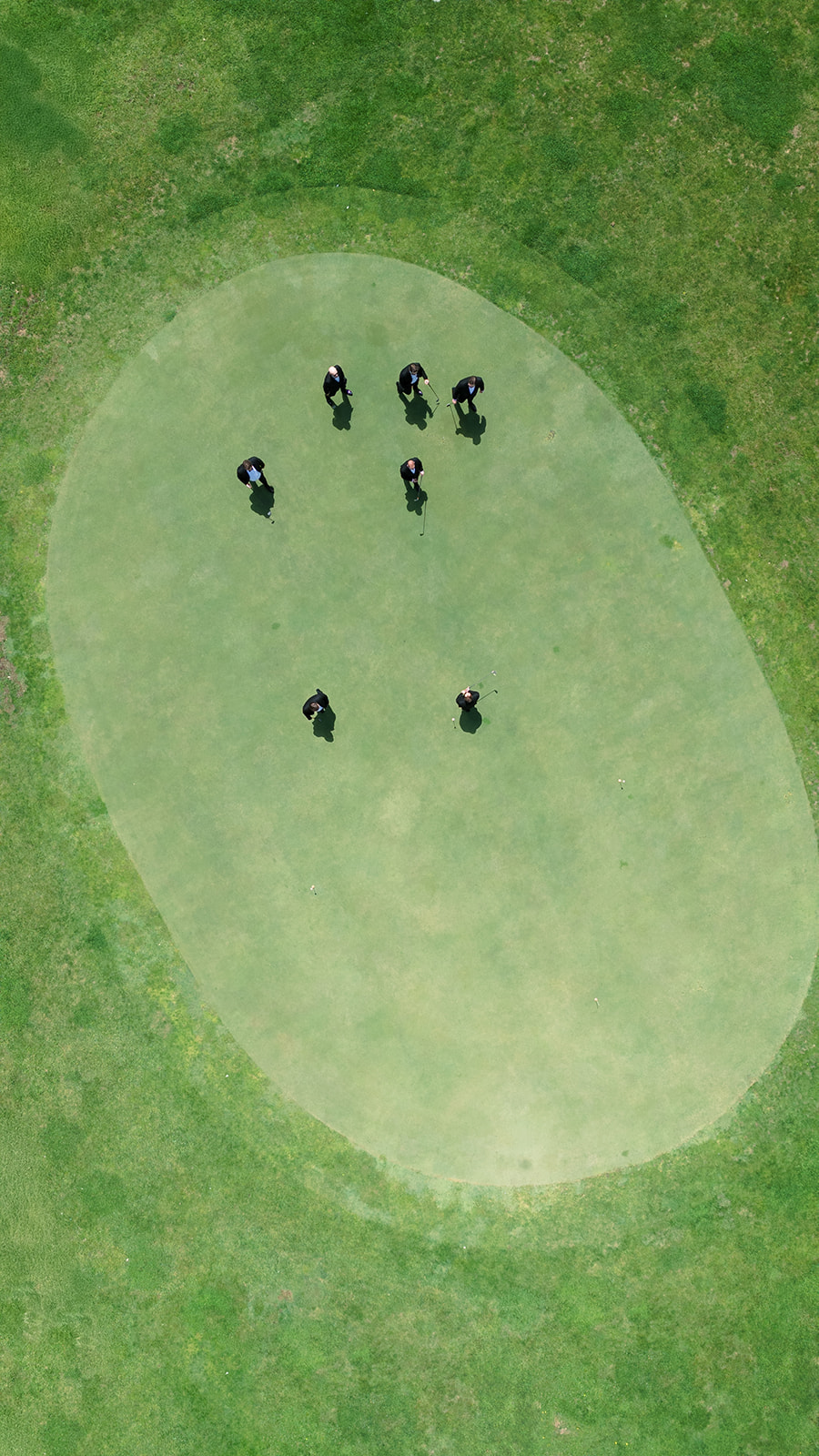 Overhead drone view of Ben and his groomsmen standing on a putting green