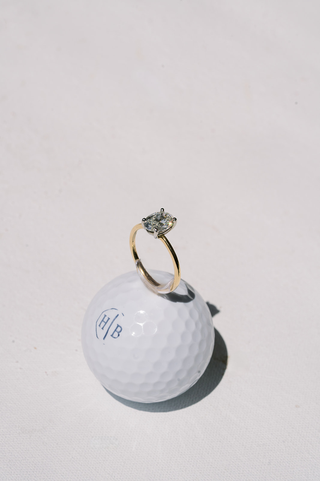 Hannalee's engagement ring balanced on a monogrammed golf ball