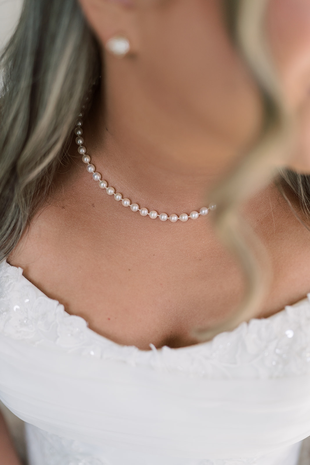 Close detail of Hannalee's pearl necklace above her wedding gown
