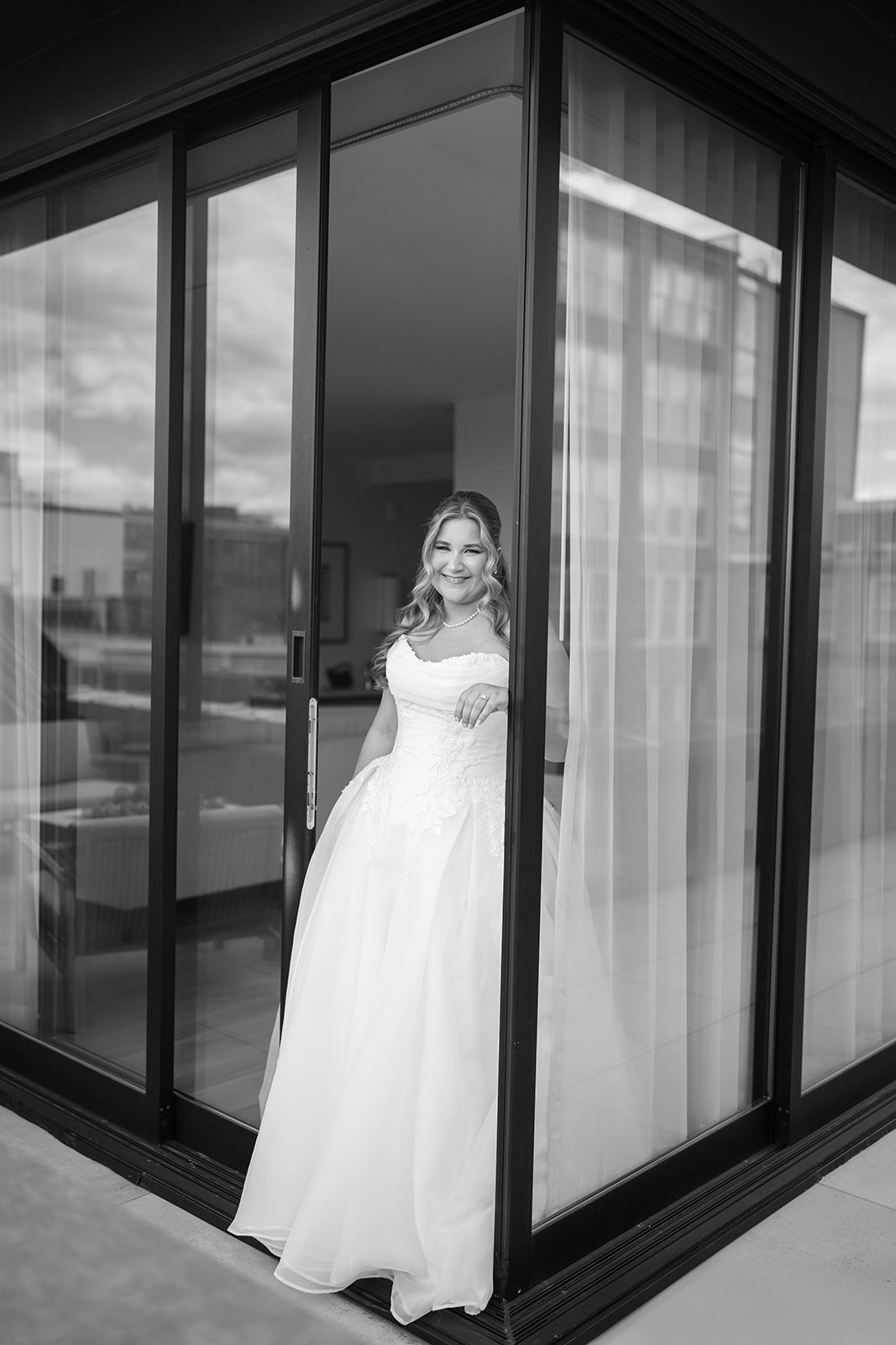 Black-and-white bridal portrait of Hannalee beside glass doors