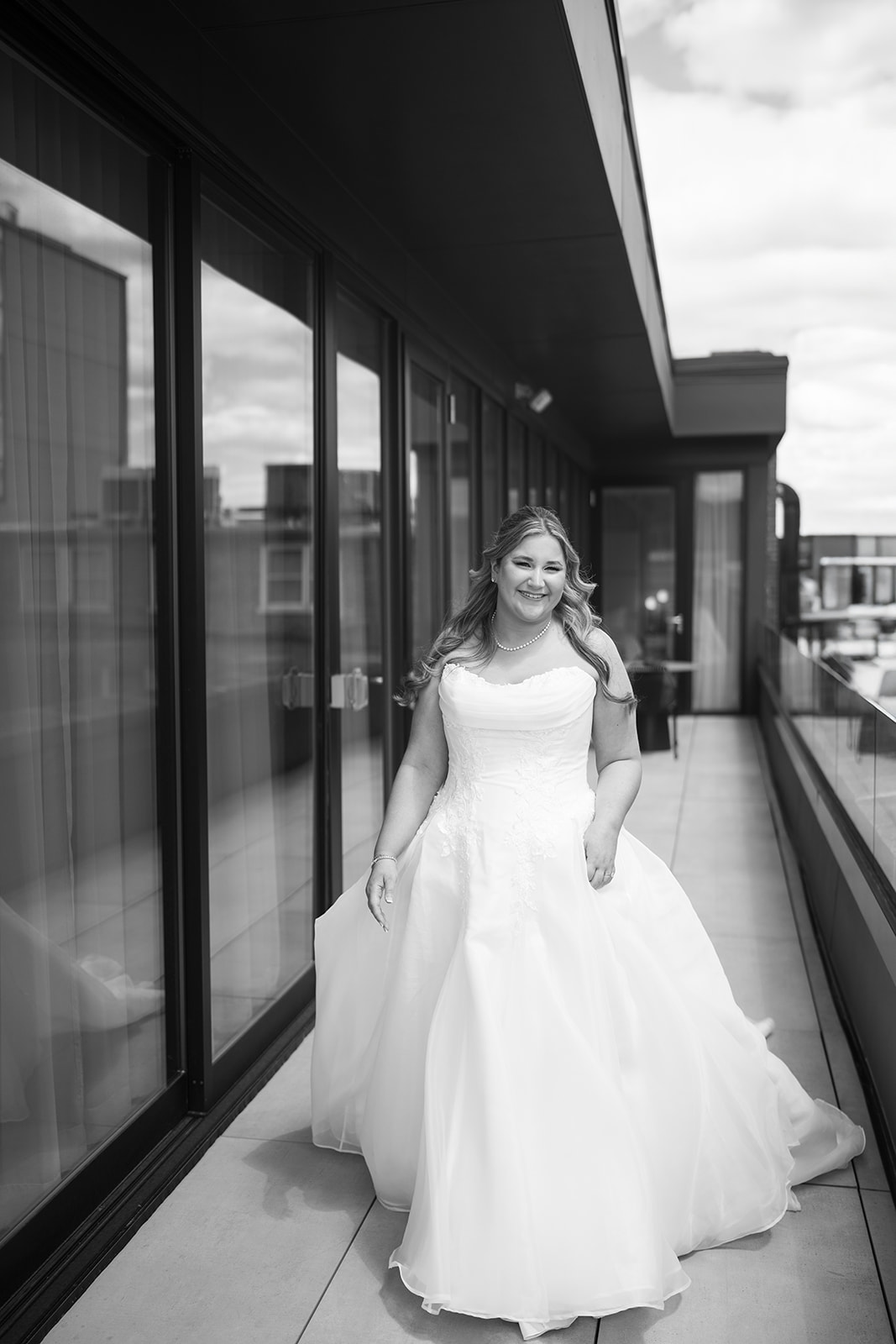 Hannalee standing beside glass doors in her wedding gown