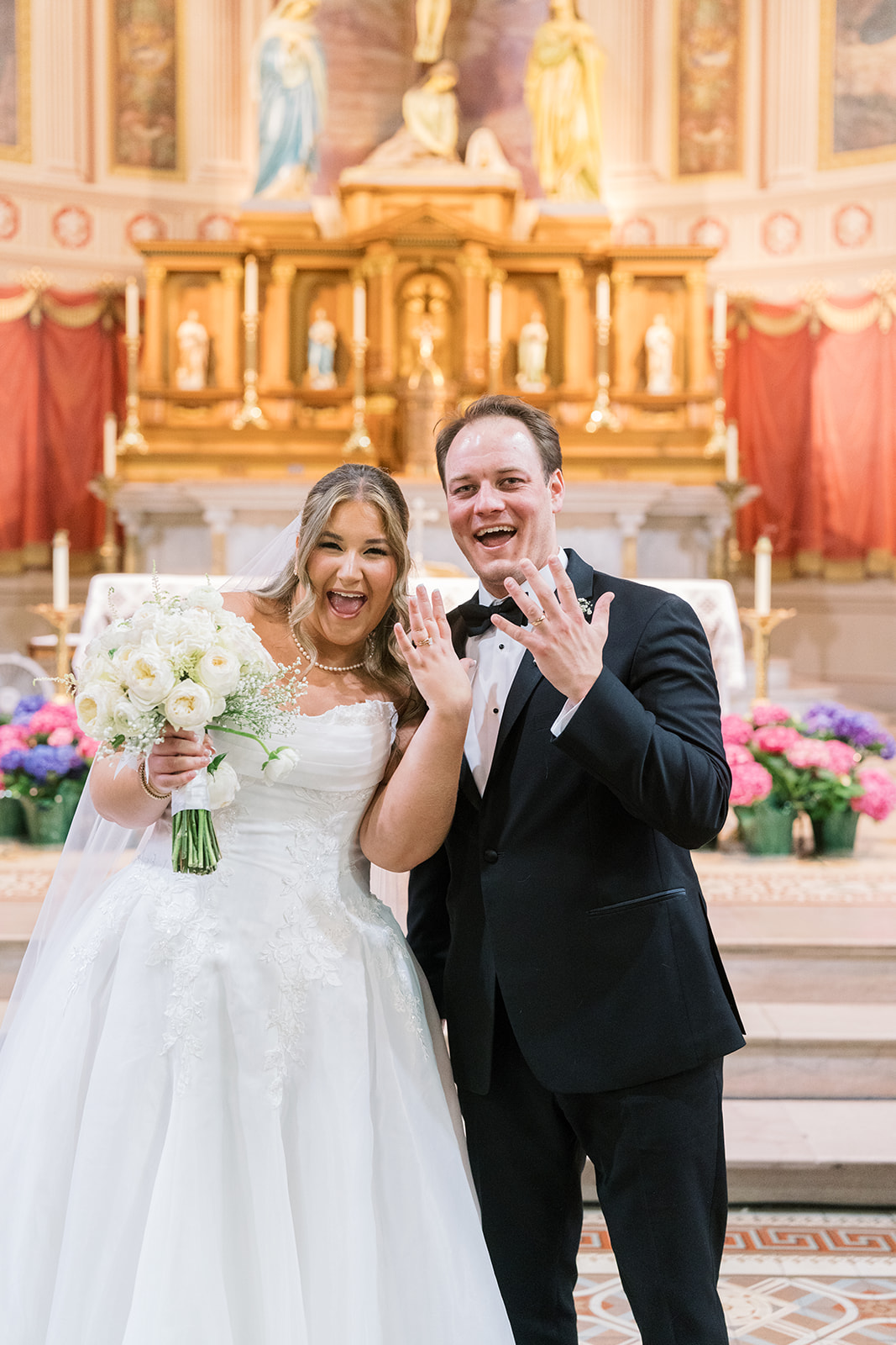 Ben and Hannalee smiling together at the front of Mother of God Church after the ceremony