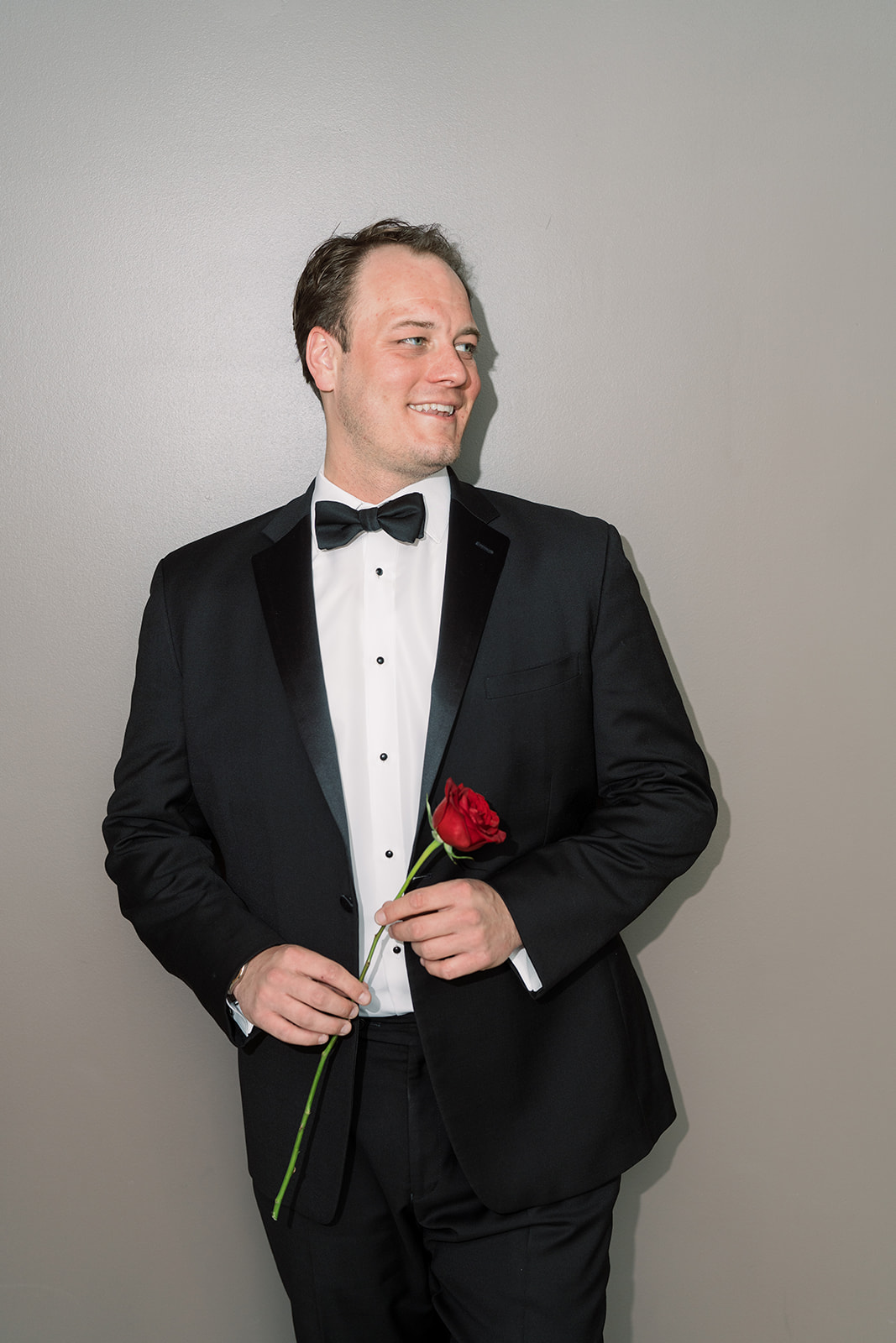 Ben holding a red rose in his tuxedo