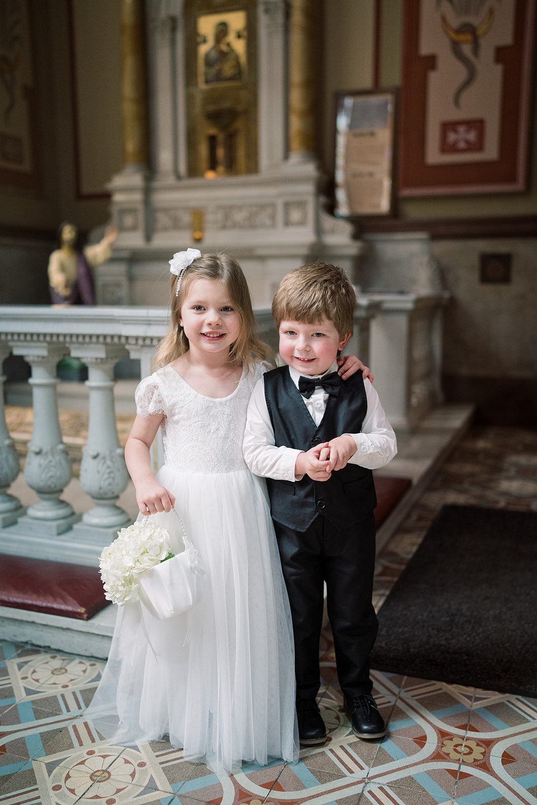 Two young members of the wedding party standing together inside Mother of God Church