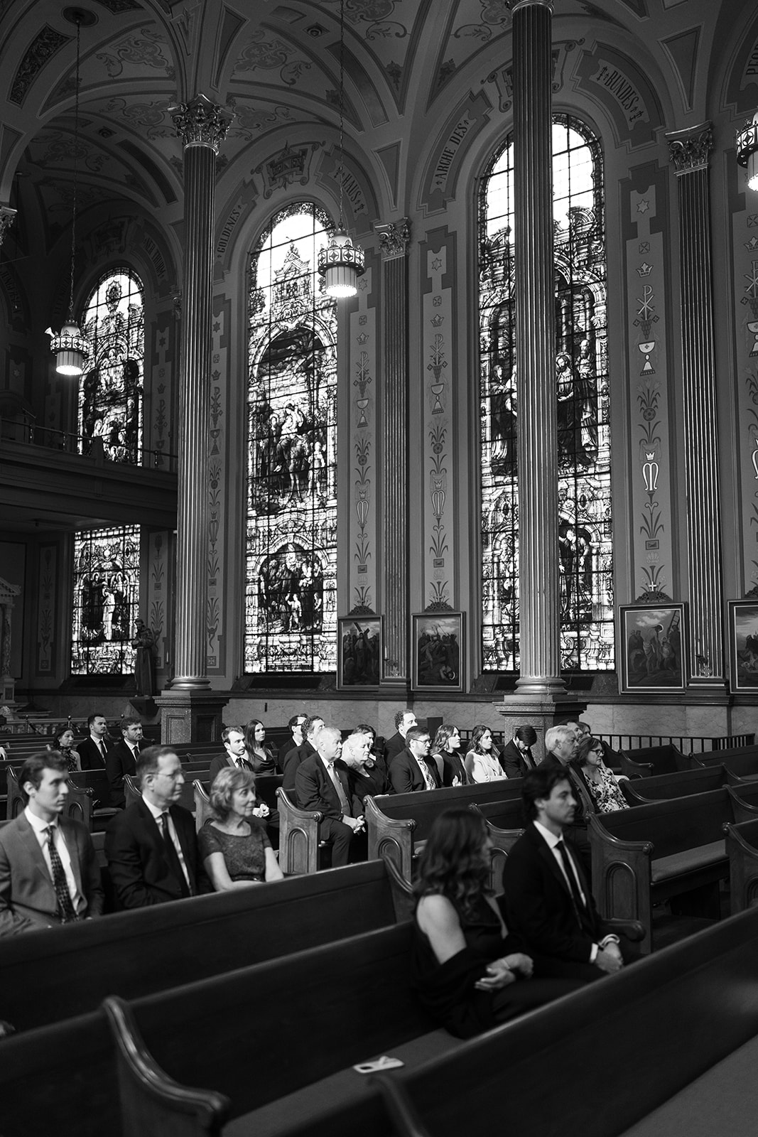 Black-and-white view of guests seated beneath the church's stained-glass windows
