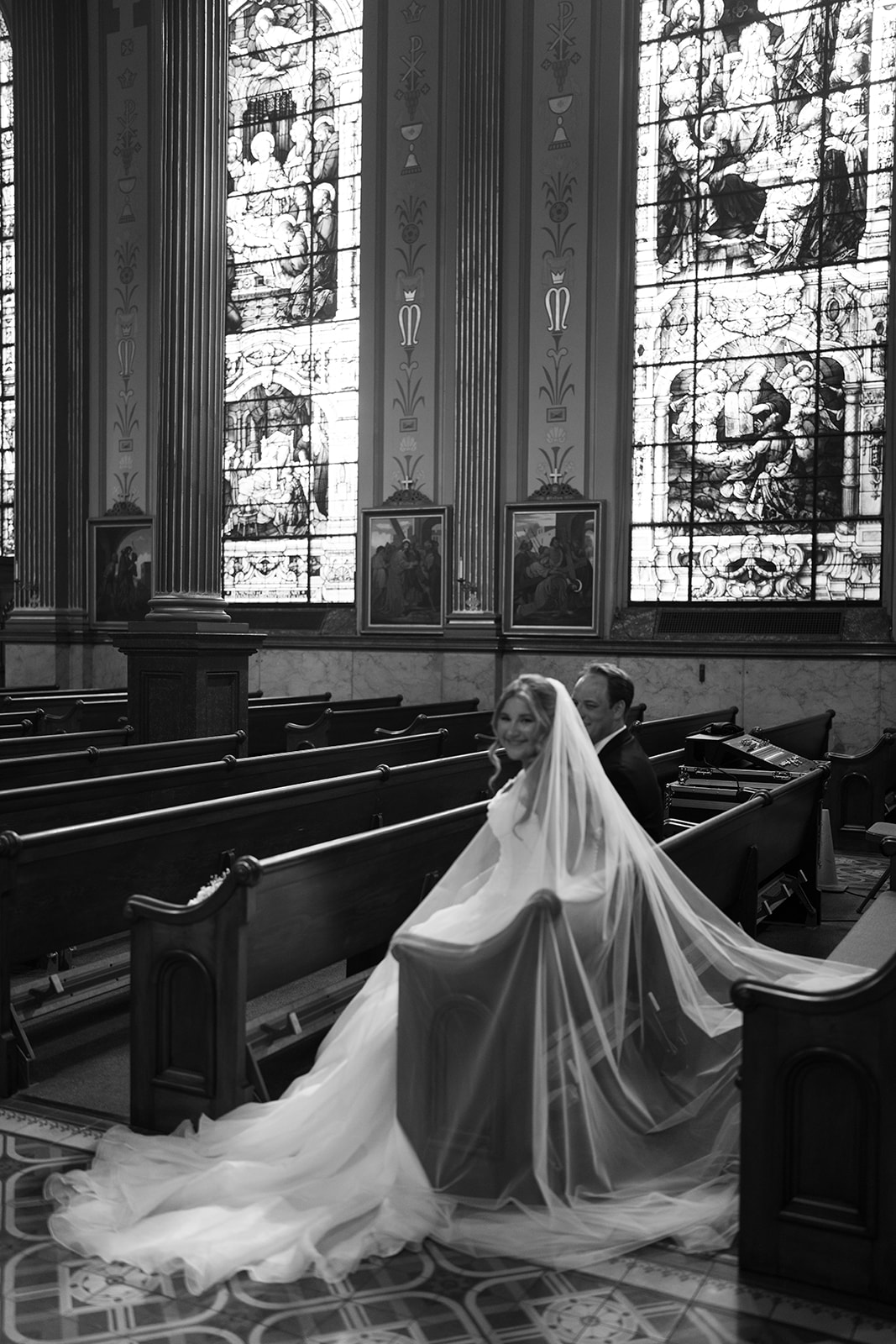 Wide black-and-white bridal portrait beneath the stained-glass windows