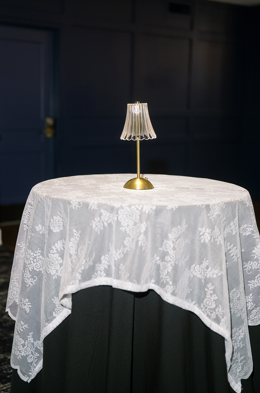 Reception cocktail table styled with lace and a small gold lamp