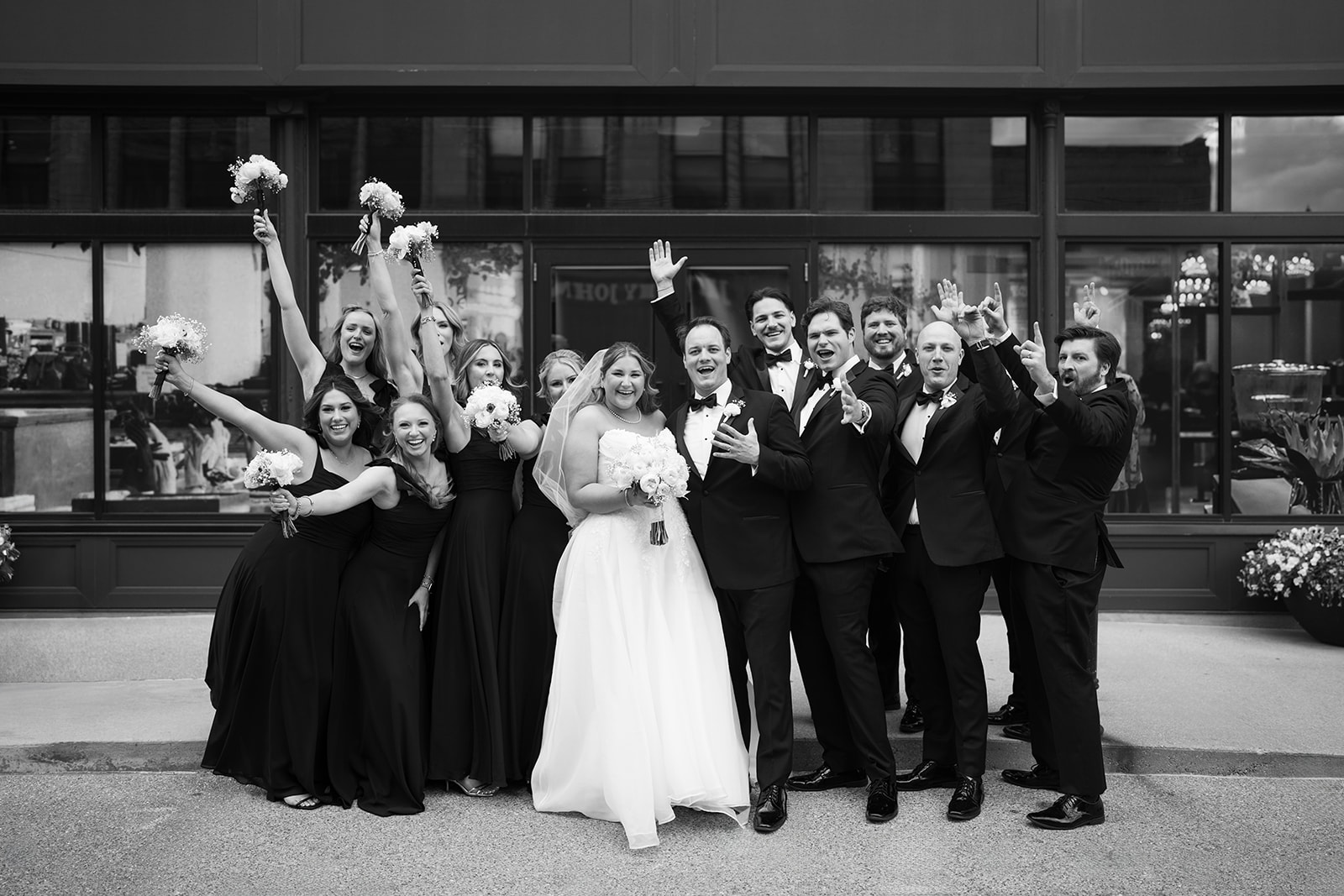 Black-and-white group portrait of Ben, Hannalee and their wedding party outside Hotel Covington