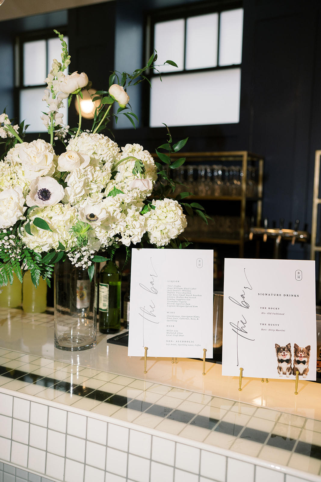 White and green floral arrangement beside reception seating cards at Hotel Covington